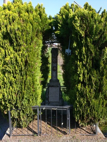 Cippo ai Saltini, monumento incastonato tra alberi, risalta in un paesaggio verde e sereno.