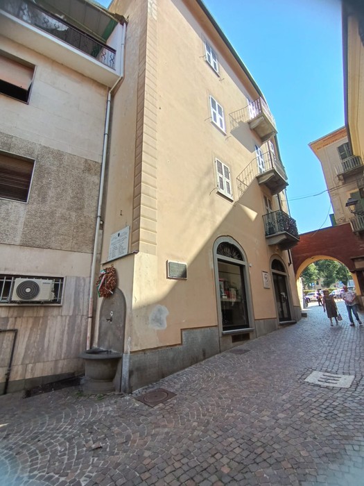 Lapide e targa commemorativa del CLN acquese su un edificio in una caratteristica via cittadina.
