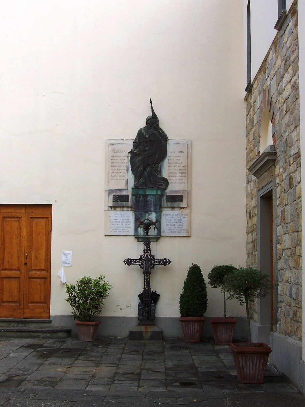 Lapide commemorativa dei caduti di Sant'Andrea a Rovezzano, con statue e croce nel contesto di un angolo urbano.