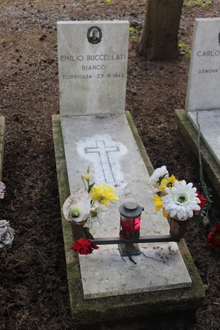 Tombe con fiori e candele, dedicate ai caduti per la Libertà, in un luogo di ricordo e rispetto.