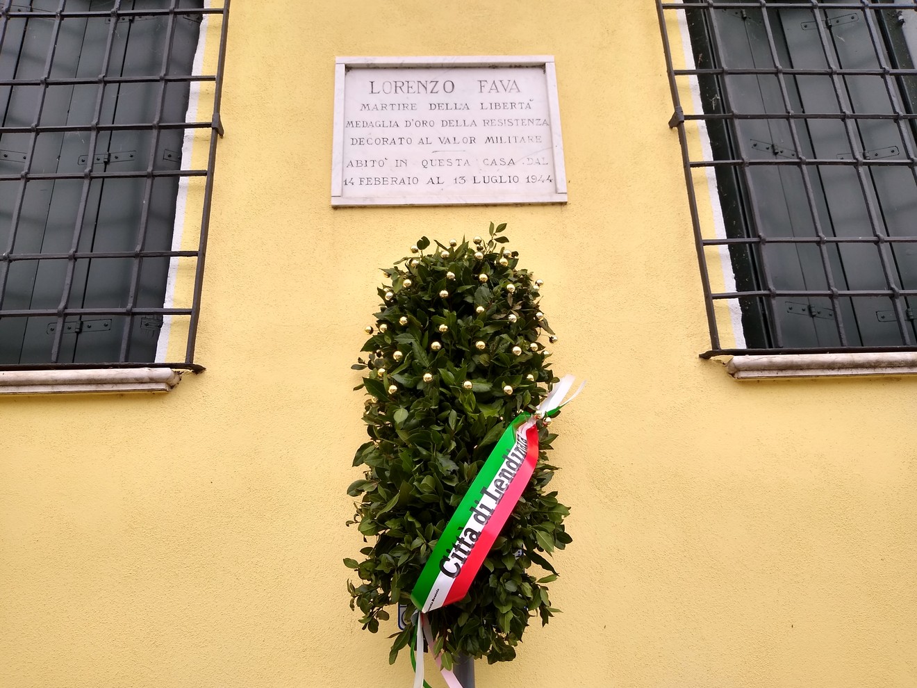 Lapide commemorativa a Lorenzo Fava, martire della libertà, con dedica e corone d'alloro.