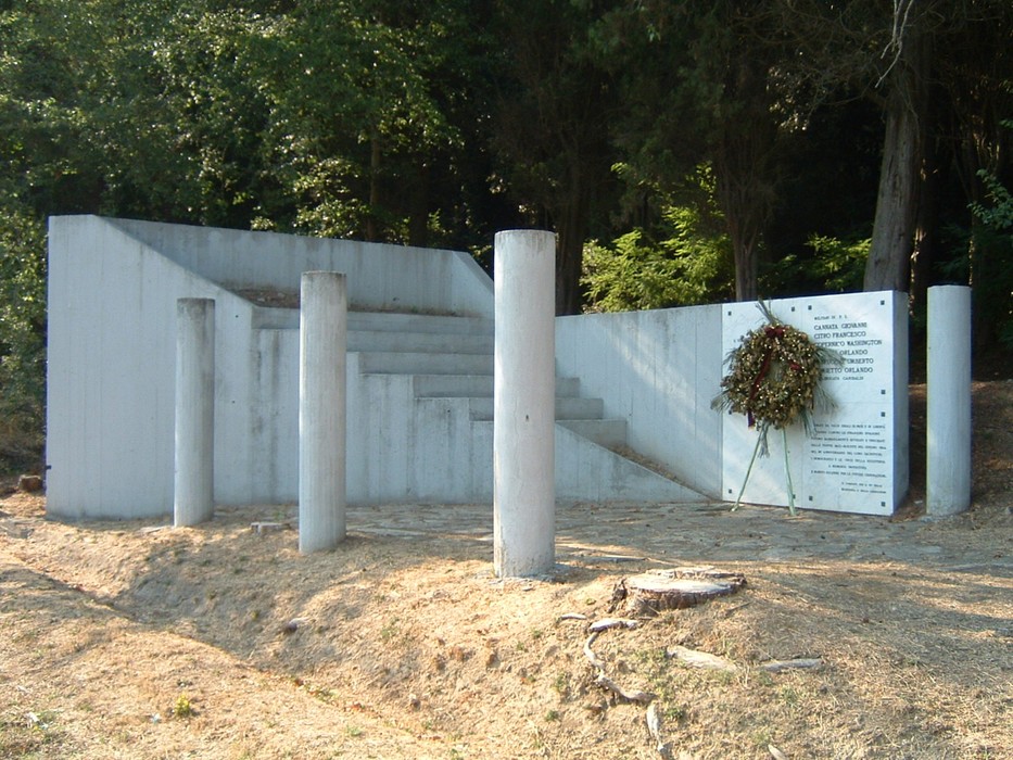 Monumento di Nugola Vecchia, dedicato alla memoria, con elementi architettonici in cemento e una corona di fiori.
