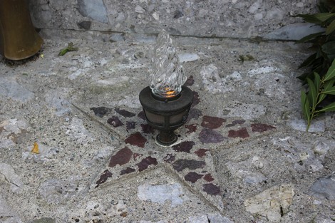 Monumento ai fratelli Pellegrini con una base a forma di stella e una fiamma accesa al centro.