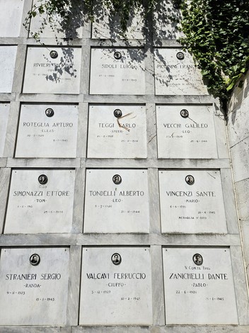 Monumento ai Caduti Partigiani con lapidi commemorative e dettagli vegetali sullo sfondo.