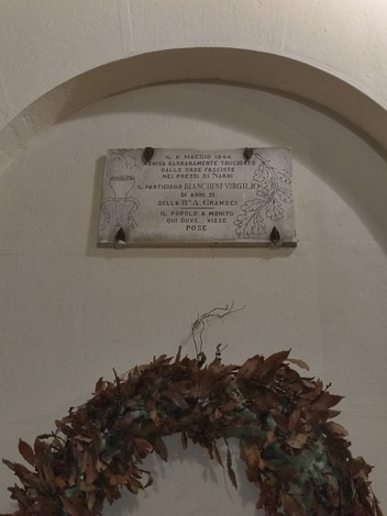 Lapide commemorativa dedicata a Bianchini, con decorazioni floreali e un ramoscello d'alloro.