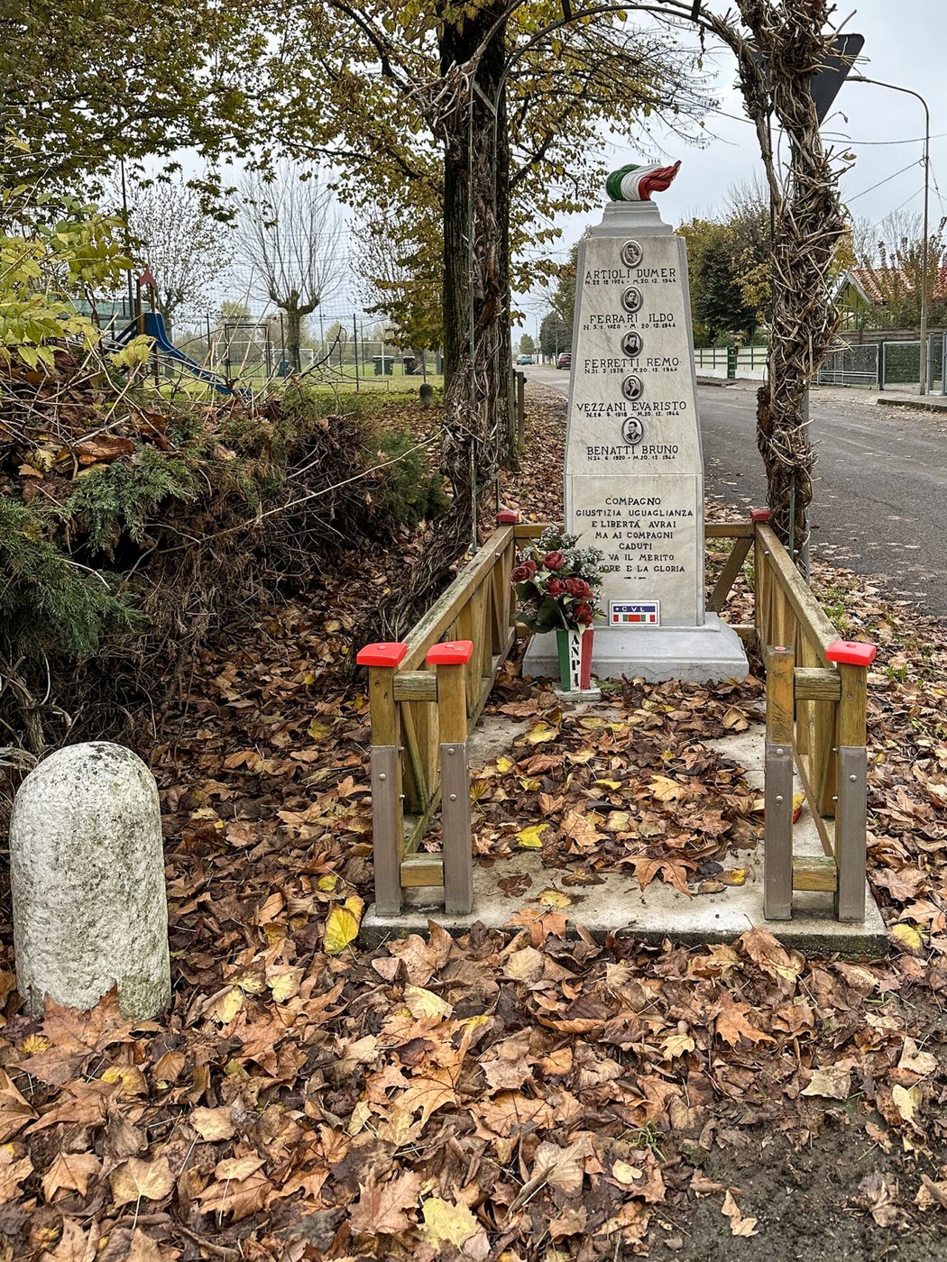 Monumento dedicato a Artioli e altri, circondato da foglie autunnali e suggestivi alberi.