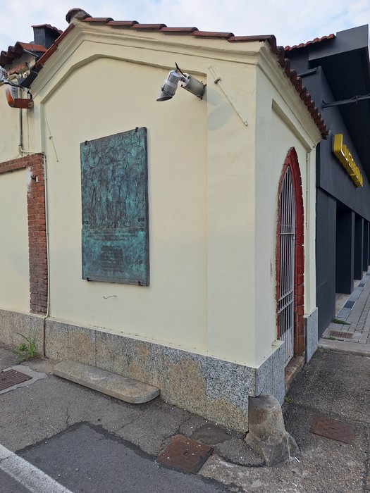 Bassorilievo in bronzo con iscrizione, fissato alla parete di un edificio all'angolo di una strada.