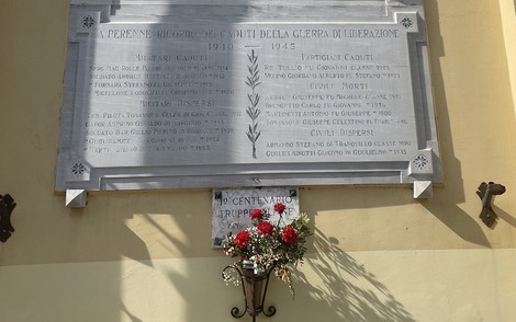 Lapide commemorativa dedicata ai caduti della guerra di liberazione, con fiori in omaggio.