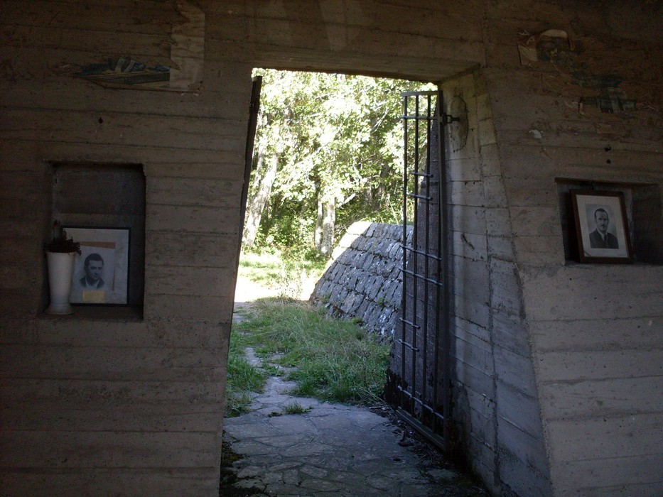 Porta d'accesso al Monumento ai partigiani, immerso nella natura e con ritratti commemorativi.