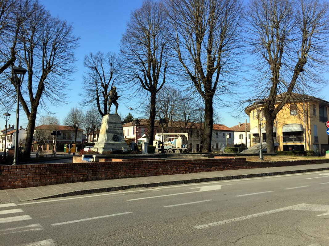 Monumento ai caduti di Bereguardo, circondato da alberi e edifici, in una piazza nel centro del paese.