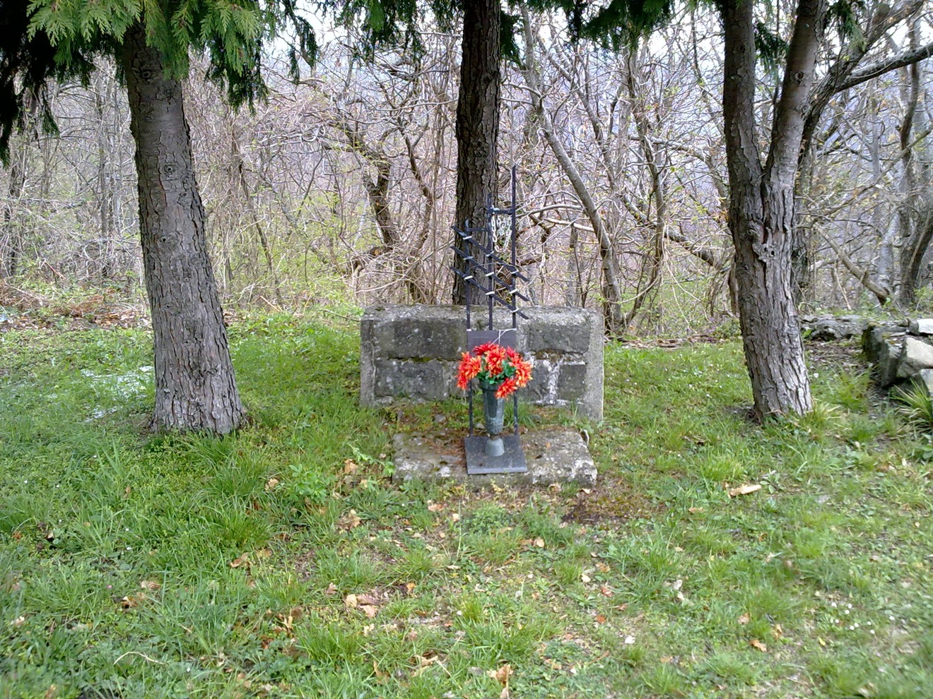 Cippo commemorativo a Ceccardi, circondato da alberi e aiuole verdi, con decorazioni floreali.