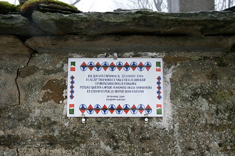 Lapide commemorativa in ricordo dei partigiani, installata su un'antica capanna.
