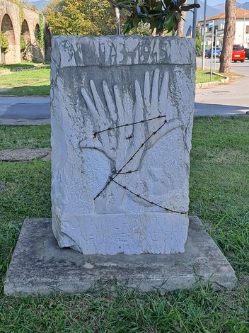 Stele commemorativa dedicata agli Internati, con incisioni e simboli significativi in un parco pubblico.