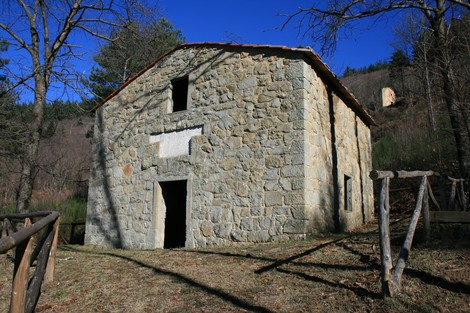 Lapidi commemorative in una antica struttura nella Pianaccia, immersa nella natura.