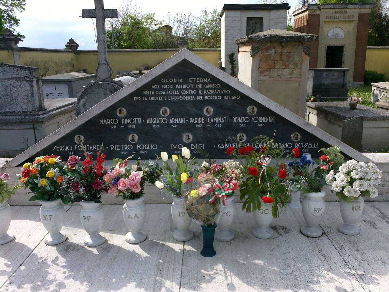 Monumento commemorativo ai caduti di Massenzatico, adornato da fiori e iscrizioni in memoria dei defunti.