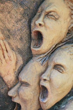Scultura di volti stilizzati che esprimono dolore e ribellione, simbolo del "Monumento delle 128 partigiane".