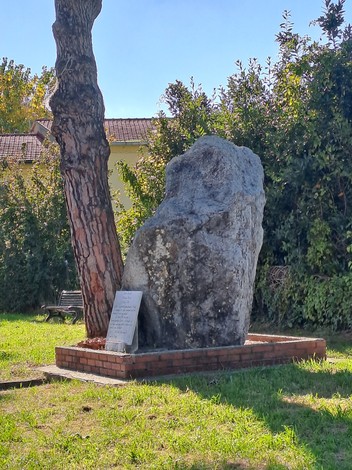 Monumento in pietra dedicato a Barachini, Barsotti e Selmi, circondato da un'area verde con alberi.
