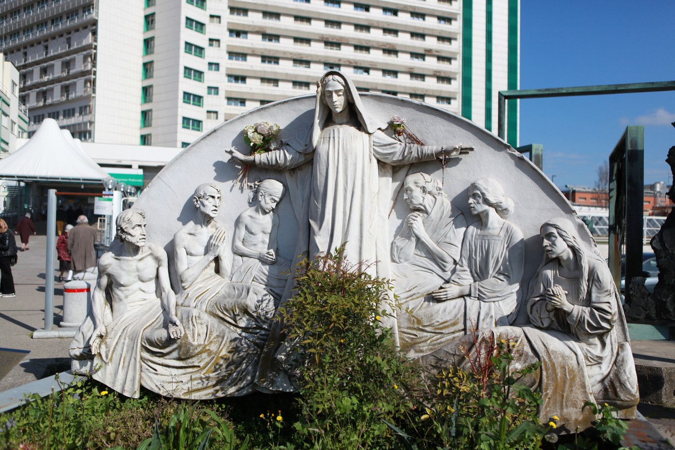 Monumento al bombardamento dell'Ospedale Maggiore, con sculture che rappresentano figure umane in celebrazione e commemorazione.