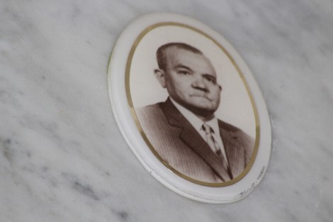 Ritratto in bianco e nero di un uomo, incastonato in una cornice su un monumento commemorativo.