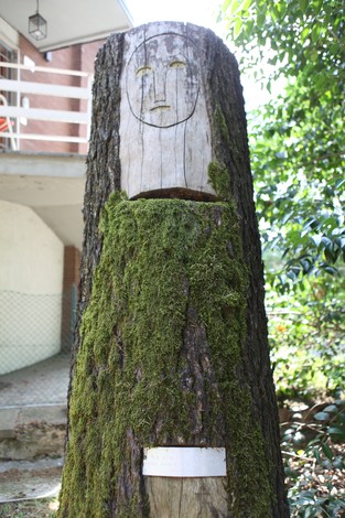 Monumento ai Caduti, un tronco d'albero con un volto scolpito e ricoperto di muschio.