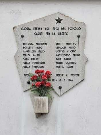 Lapide commemorativa dedicata ai caduti per la libertà con decorazione floreale.