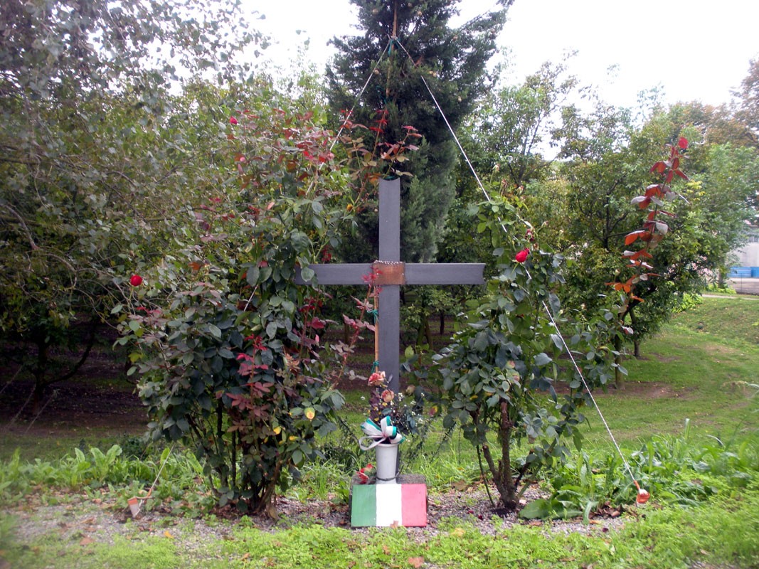 Croce in memoria dei partigiani, circondata da vegetazione, simbolo di resistenza e libertà.