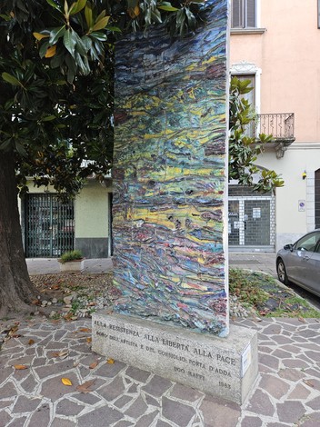 Monumento alla Resistenza, alla Libertà e alla Pace, con un grande pannello artistico tra alberi e strade.
