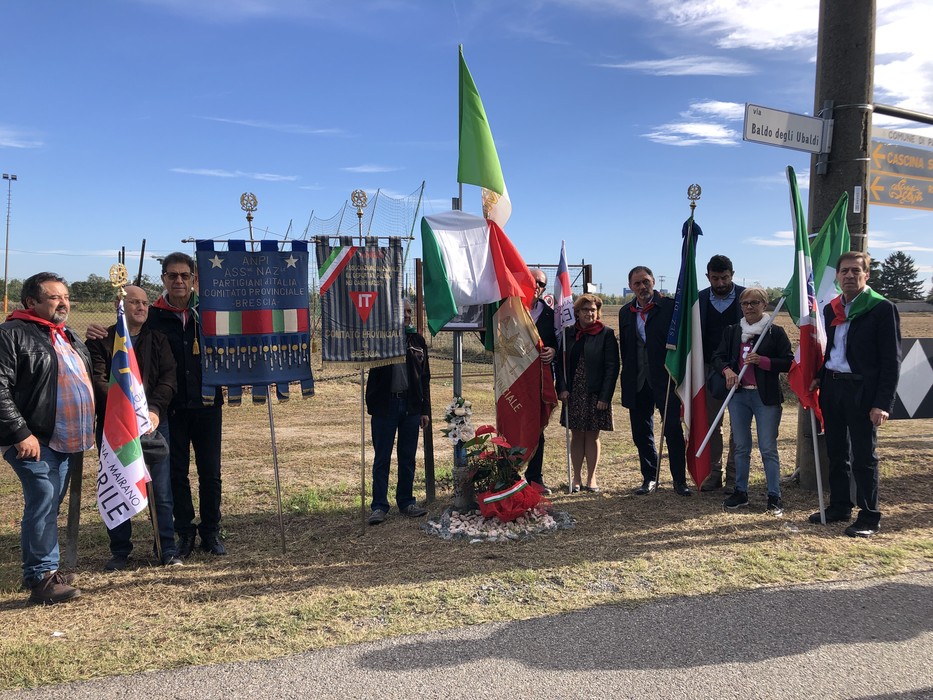 Celebrazione congiunta in onore di Ferrari, con bandiere e fiori in un evento commemorativo.