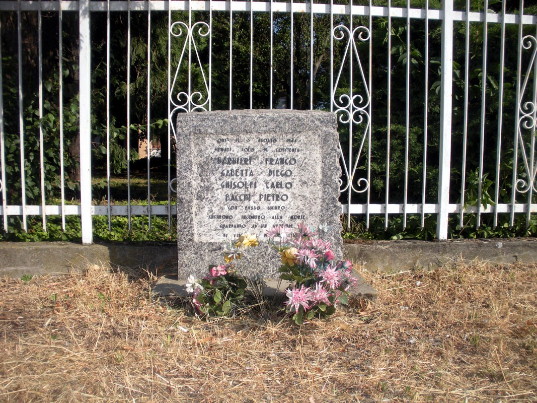 Monumento commemorativo dedicato ai fucilati della via Emilia, con fiori e inscrizioni in memoria delle vittime.