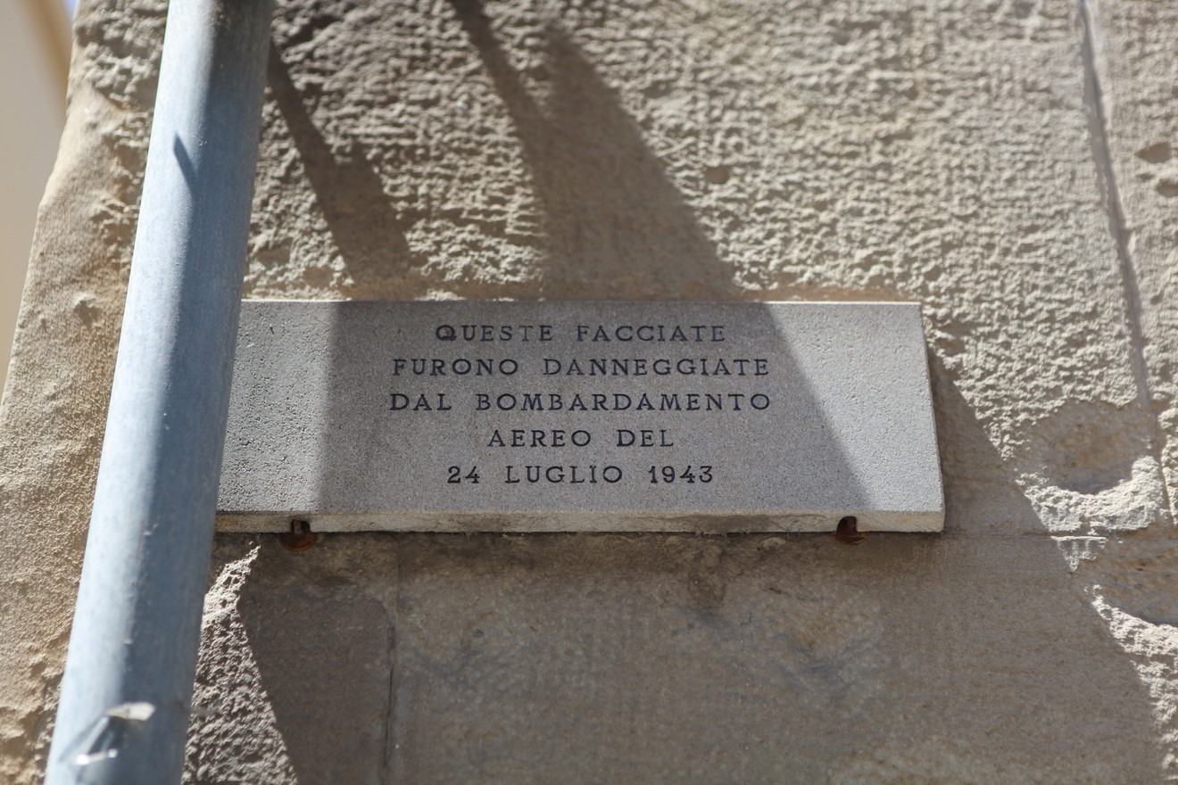Lapide commemorativa che ricorda i danni subiti dalle facciate nel bombardamento del 24 luglio 1943.
