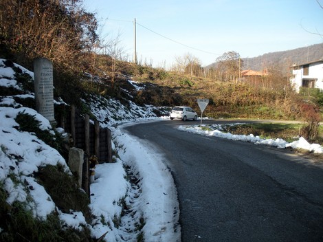 Cippo a Bricchetti su una strada circondata da neve e natura, in un paesaggio montano.
