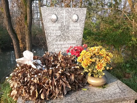 Lapide commemorativa con fiori e corona in memoria di Fagnani e Garanzini, immersa nella natura.