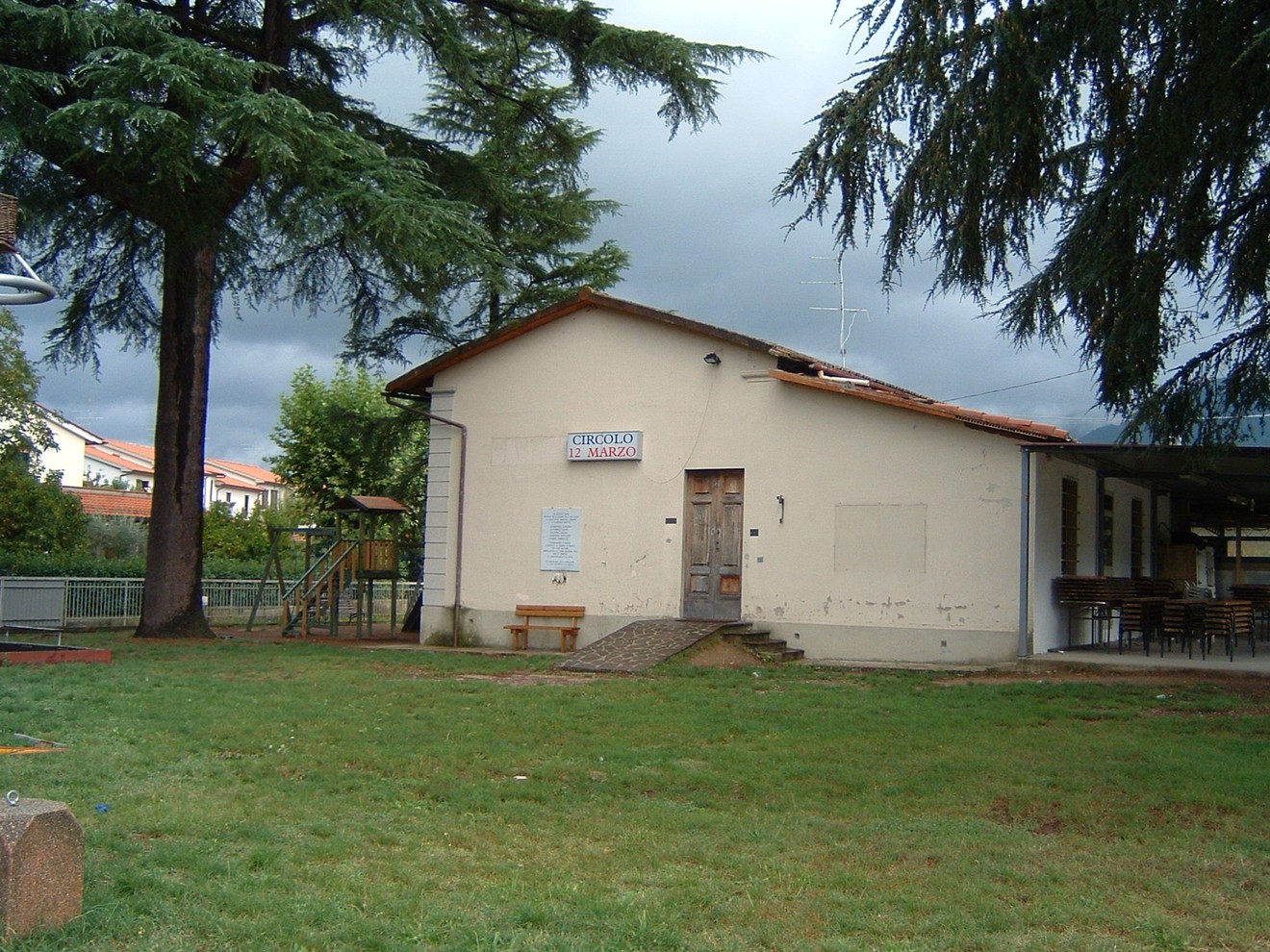 Lapide commemorativa del Circolo 12 Marzo, situata in un'area verde con una struttura attigua.