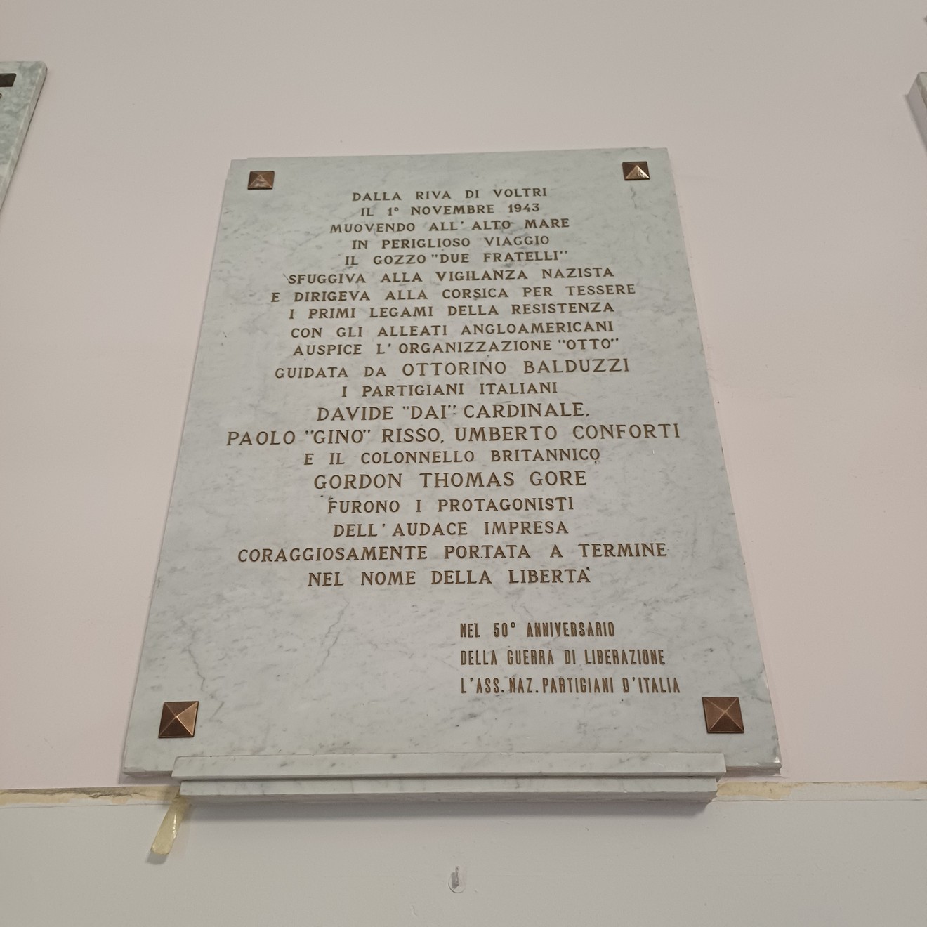 Lapide in marmo con lunga iscrizione, fissata a una parete interna con borchie agli angoli.