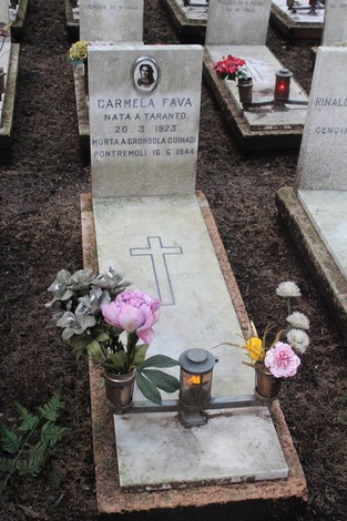 Tombe perpetue dei caduti per la Libertà, con fiori e candele su lastre tombali in un cimitero.