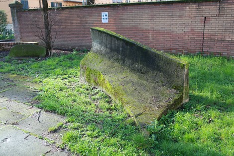 Monumento alla Resistenza, struttura in pietra ricoperta di muschio, immersa nel verde e circondata da un ambiente urbano.