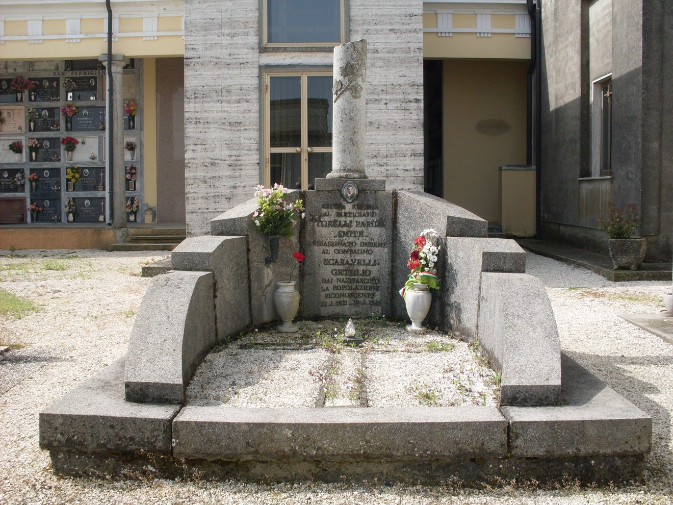 Monumento commemorativo a Torelli e Scaravelli, con elementi floreali e una struttura in pietra.