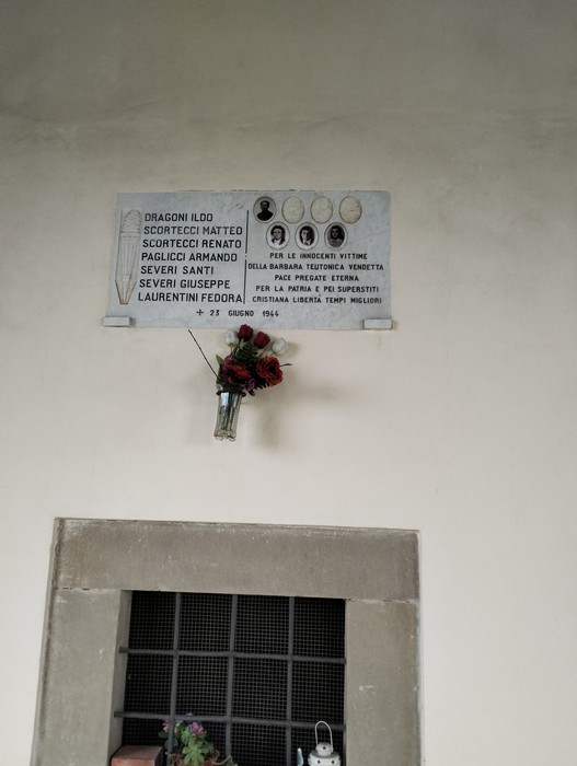 Lapide commemorativa ai caduti di Valloni, con nomi e omaggi floreali.