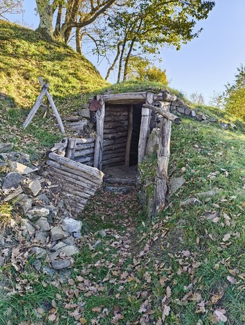 Entrata di un rifugio nella natura, simbolo di memoria della guerra e della resistenza storica.
