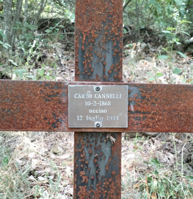 Croce commemorativa di Carlo Cannelli, ucciso il 12 luglio 1944, in un contesto di verde natura.
