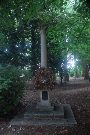 Monumento con colonna e corona di alloro, immerso nella vegetazione del Parco delle Rimembranze.