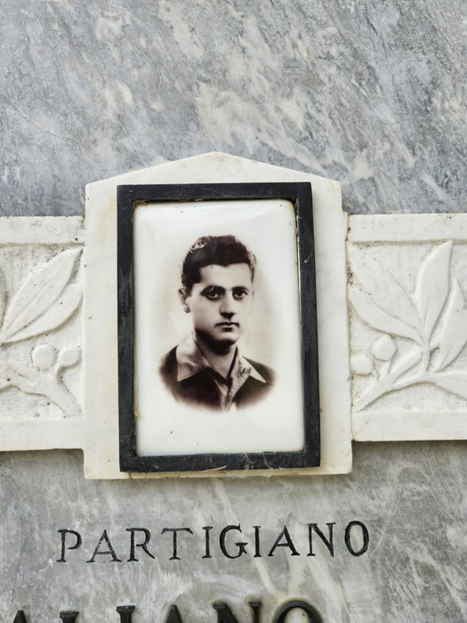 Lapide commemorativa di un partigiano, con una foto incassata su marmo decorato.