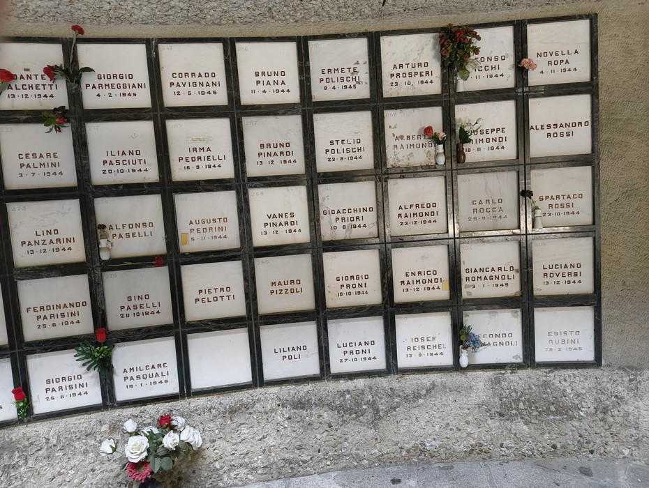 Monumento Ossario dedicato ai caduti partigiani, con targhe commemorative e fiori di ricordo.
