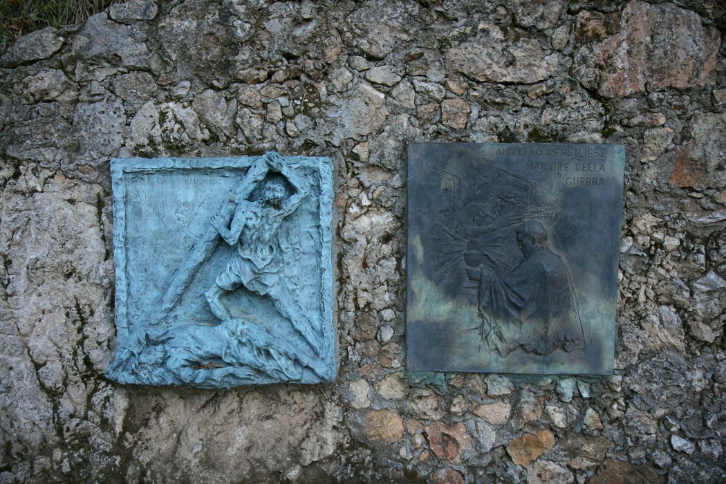 Rappresentazione artistica della Via Crucis di Sant'Anna di Stazzema, con pannelli in rilievo su muro roccioso.