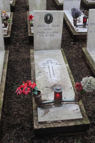 Tombe commemorate con fiori e candele, dedicate ai caduti per la libertà, in un luogo di memoria e rispetto.
