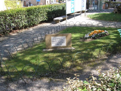 Cippo commemorativo dedicato a Ottaviani, situato in un giardino curato con aiuole fiorite.