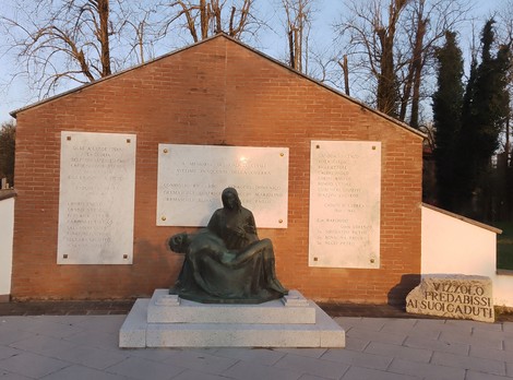 Monumento ai caduti con statua commemorativa e pannelli informativi, immerso in un contesto naturalistico.