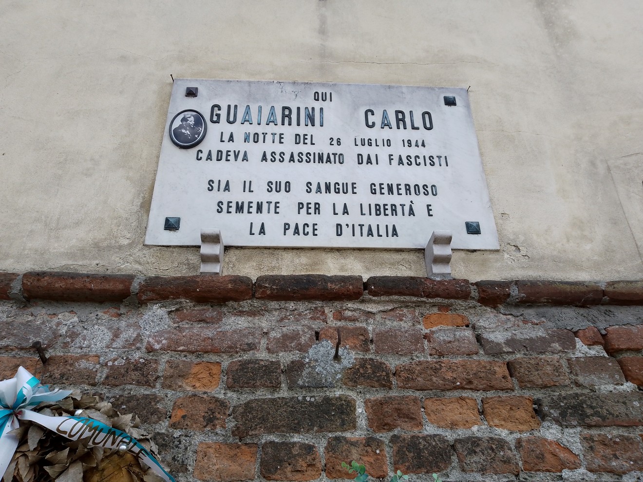 Lapide commemorativa di Guaiarini Carlo, assassinato dai fascisti nel 1944, situata su un muro di mattoni.
