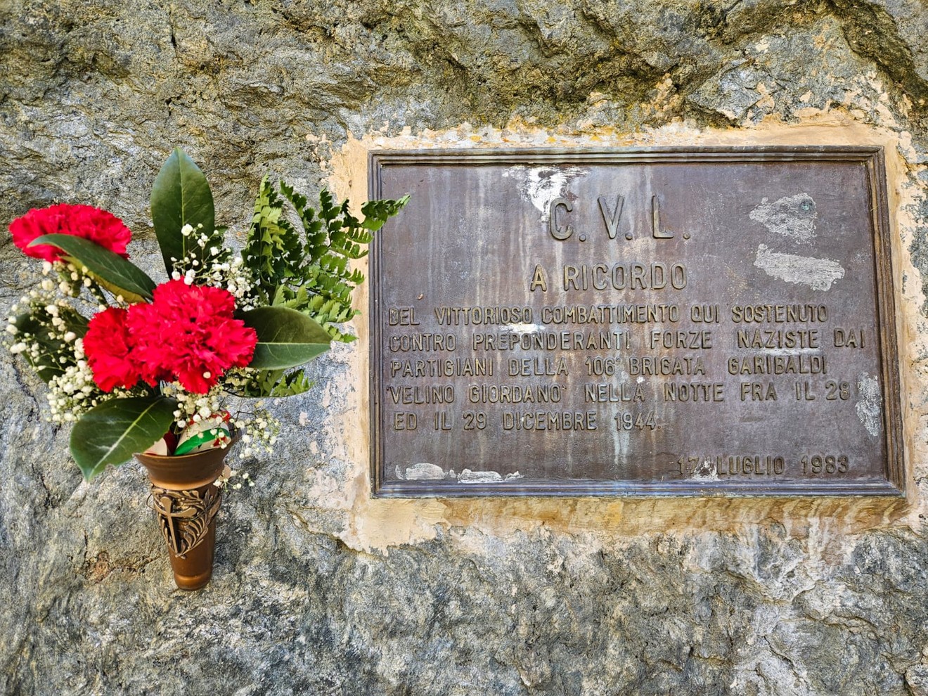 Lapide commemorativa della 106a brigata, con fiori freschi in omaggio ai caduti.