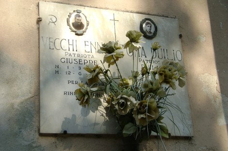 Lapide commemorativa dedicata ai patrioti Vecchi e Toma, con fiori decorativi, in omaggio ai caduti.
